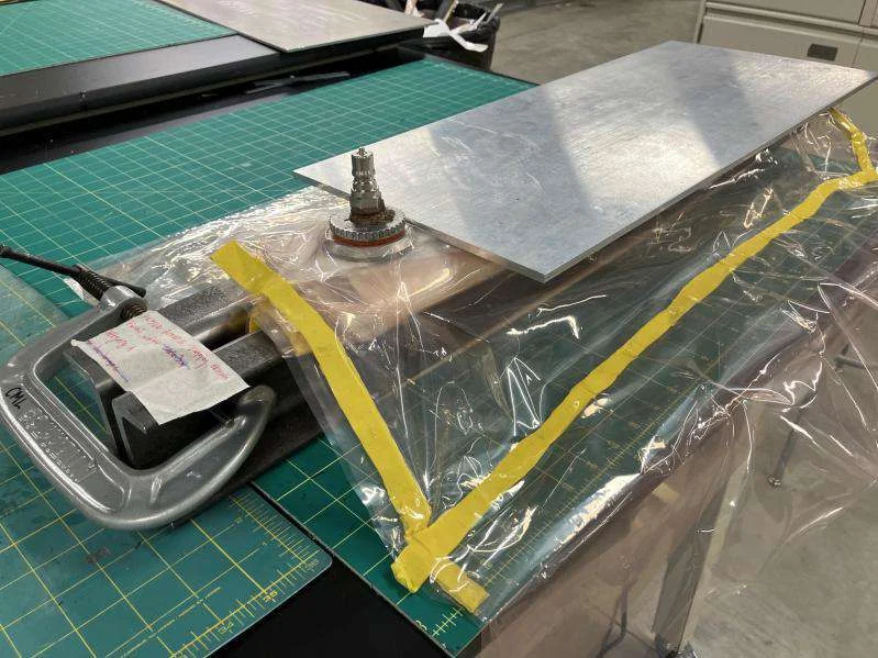 Composite beam bagged and restrained in fabrication tooling