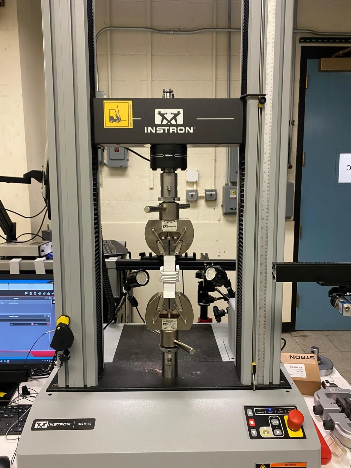 Paper bellows specimen and printed fixtures mounted in a tensile testing frame